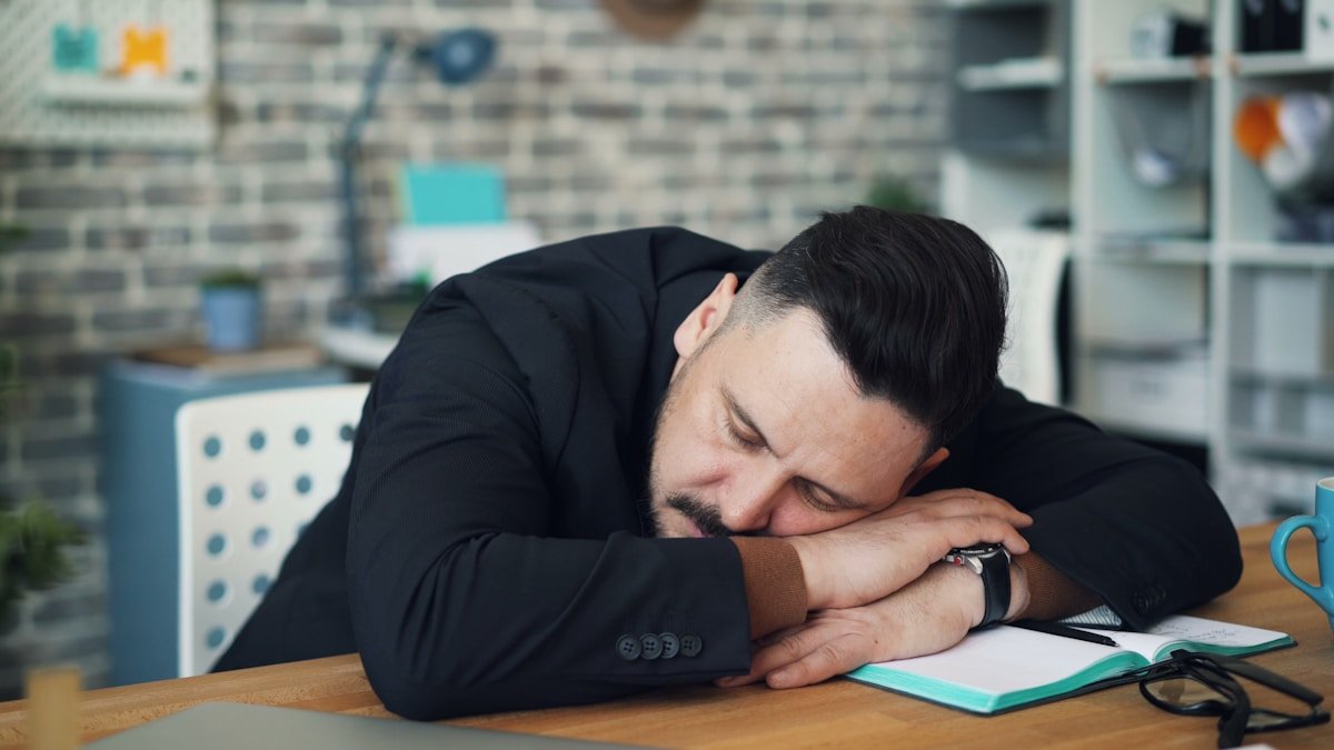 Tired person rubbing their eyes in front of a computer screen