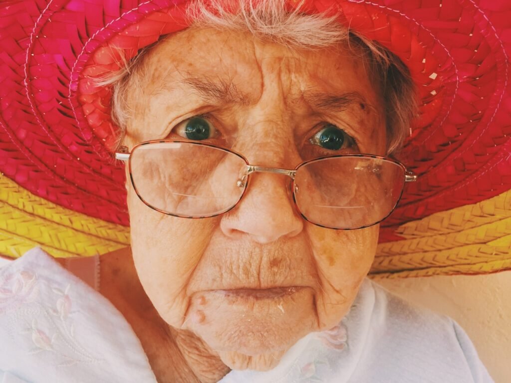 Elderly woman instilling eye drops into her eye after cataract surgery