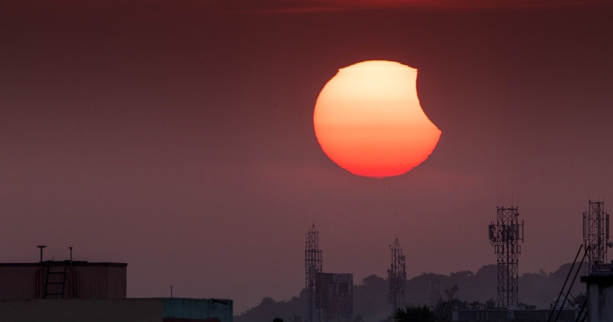 Éclipse solaire partielle au-dessus d'une ville, Soleil bas sur l'horizon en soirée