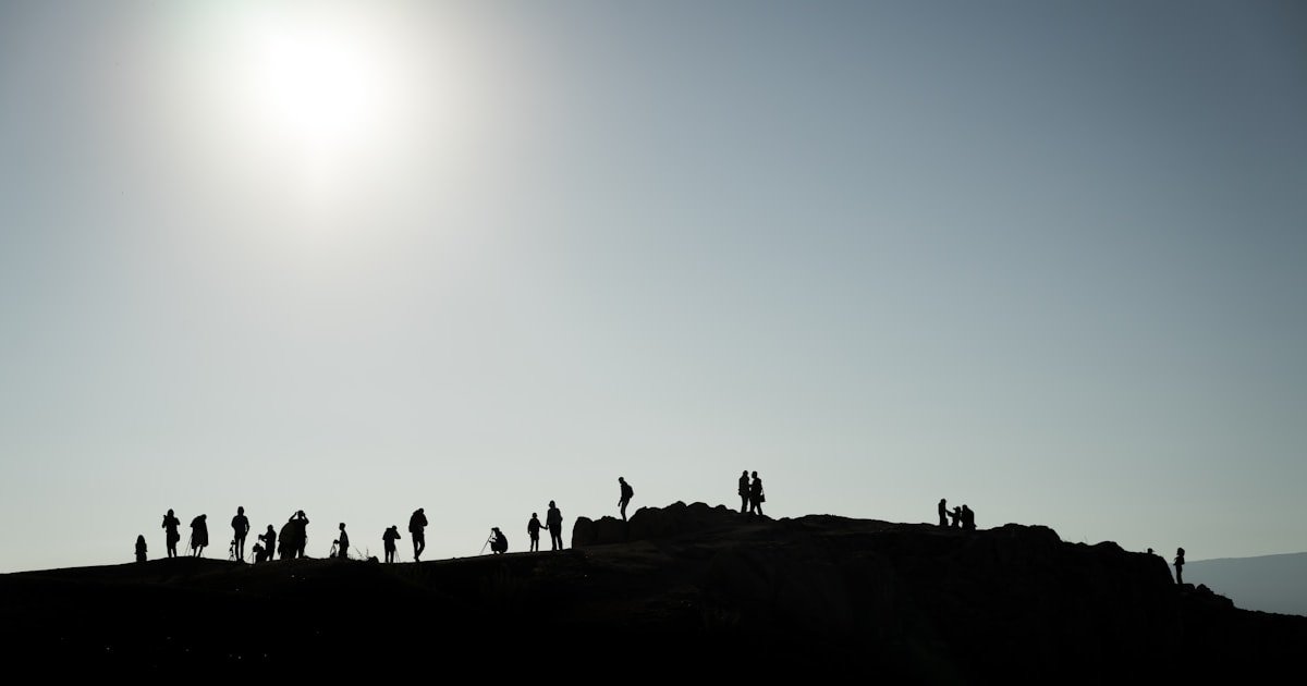 Groupe de personnes rassemblées sur une crête pour observer le Soleil